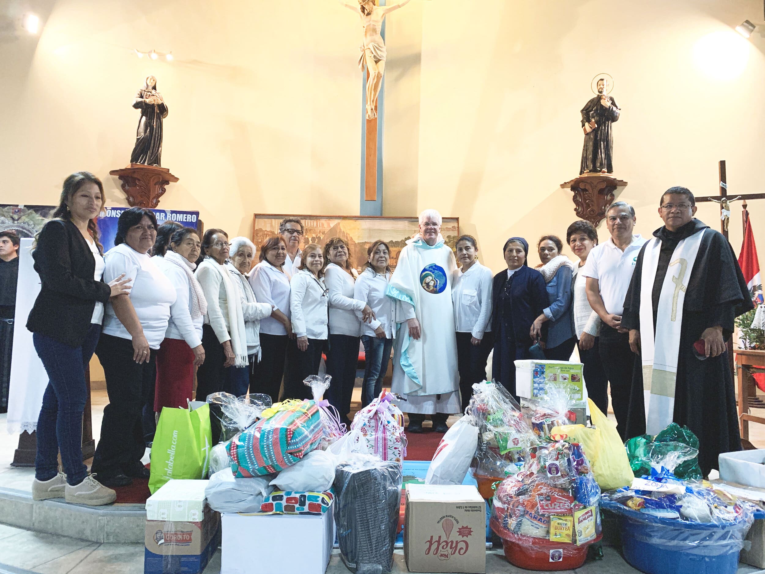 Group of people with a Friar in front of a collection of gifts